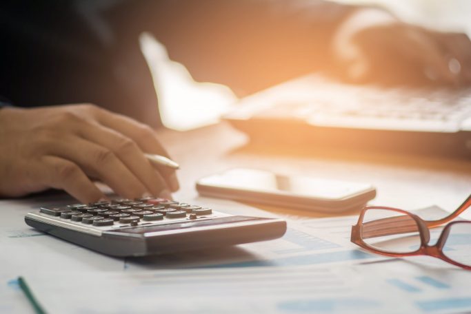 A,Businessman,Analyzing,Investment,Charts,At,His,Workplace,And,Using